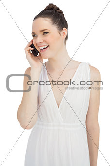 Smiling pretty model in white dress having phone call