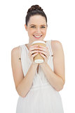 Smiling natural model in white dress drinking coffee