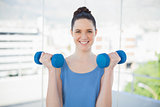 Smiling sporty woman exercising with dumbbells