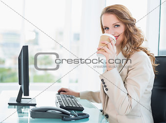 Smiling pretty businesswoman drinking coffee