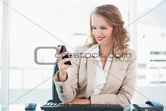 Pleased pretty businesswoman looking at her mobile phone