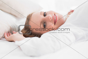 Smiling pretty woman lying on her bed