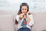 Peaceful cute model pointing at camera listening to music
