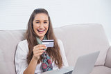 Smiling young model using her credit card to buy online