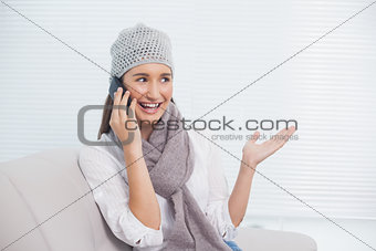 Smiling pretty brunette with winter hat on having a phone call