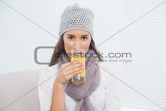 Pretty brunette with winter hat on drinking orange juice