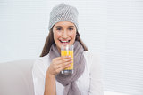 Pretty brunette with winter hat on holding glass of orange juice
