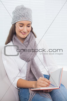 Pretty brunette with winter hat on writing on her notebook