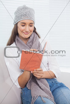 Happy pretty brunette with winter hat on writing on notebook