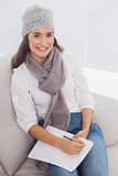 Smiling brunette with winter hat on writing