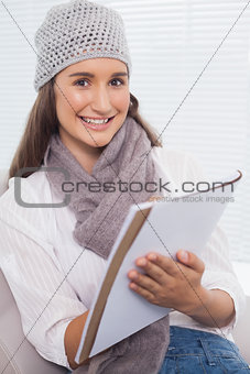 Cheerful brunette with winter hat on writing