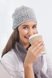 Smiling brunette with winter hat on drinking coffee
