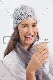 Cheerful brunette with winter hat on holding mug of coffee
