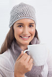 Smiling brunette with winter hat on holding cup of coffee