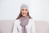Smiling brunette with winter hat on sitting on cosy sofa