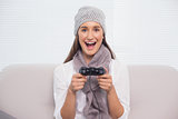 Smiling brunette with winter hat on playing video games