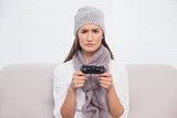 Frowning brunette with winter hat on playing video games