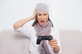 Furious brunette with winter hat on playing video games