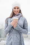 Smiling pretty brunette with winter clothes on holding coffee
