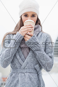 Pretty brunette with winter clothes on drinking coffee