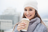 Smiling brunette with winter clothes on holding mug of coffee