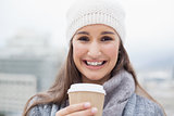 Happy brunette with winter clothes on holding mug of coffee