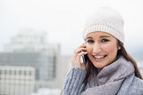 Smiling brunette with winter clothes on having a call