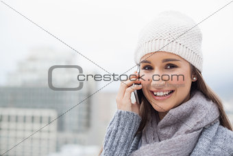 Smiling brunette with winter clothes on having a call
