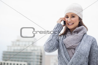 Content brunette with winter clothes on having a call
