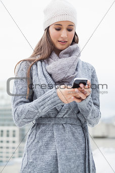 Focused woman with winter clothes on text messaging