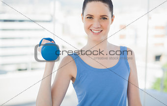 Smiling sporty woman exercising with dumbbell