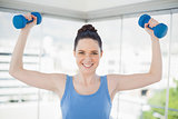 Smiling fit woman exercising with dumbbells