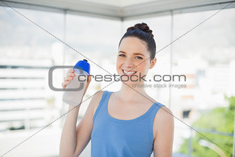 Pretty fit woman holding plastic flask