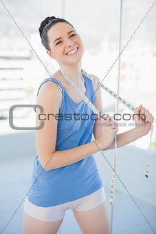Cheerful slender woman in sportswear holding measuring tape