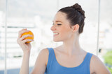 Cheerful slender woman in sportswear holding orange