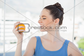Cheerful slender woman in sportswear holding orange
