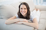 Cheerful pretty woman lying on a cosy couch