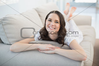 Smiling pretty woman lying on a cosy couch