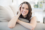 Smiling cute woman lying on a cosy couch