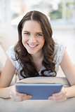 Smiling woman lying on a cosy couch holding tablet pc