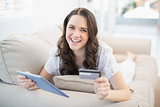 Smiling woman using her credit card to buy online