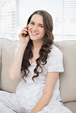Cheerful young woman in pyjamas having phone call