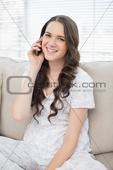 Cheerful young woman in pyjamas having phone call