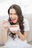 Pretty woman in pyjamas eating fruity cereal