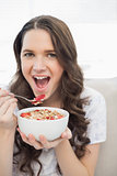 Cute young  woman in pyjamas eating fruity cereal