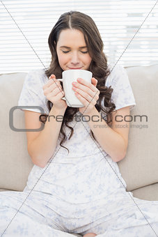 Relaxed young woman in pyjamas having coffee