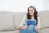 Casual woman on cosy couch holding tablet pc