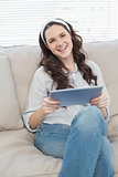 Happy casual woman on cosy couch using tablet pc