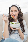 Gorgeous casual woman on cosy couch eating salad