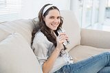 Gorgeous casual woman on cosy couch holding glass of water